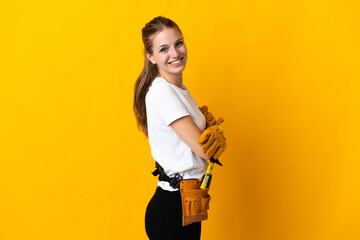 Young electrician woman isolated on yellow background with arms crossed and looking forward