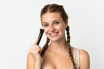 Obraz premium Young caucasian woman isolated on white background holding makeup brush