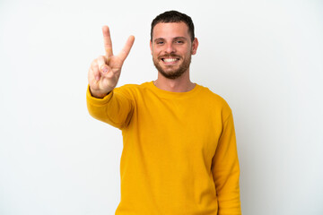 Young Brazilian man isolated on white background smiling and showing victory sign