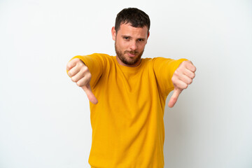 Young Brazilian man isolated on white background showing thumb down with two hands