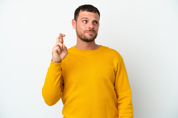 Young Brazilian man isolated on white background with fingers crossing and wishing the best