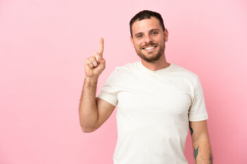 Young Brazilian man isolated on pink background pointing up a great idea