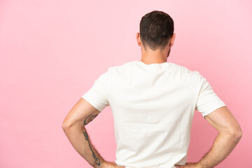 Young Brazilian man isolated on pink background in back position