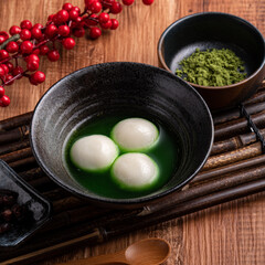 Matcha big tangyuan and matcha soup on wooden table.