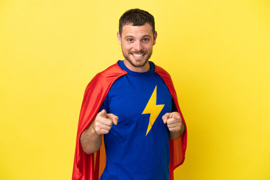 Super Hero Brazilian man isolated on yellow background pointing to the front and smiling
