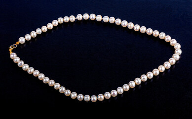 Pearl necklace on a dark blue leatherette background.