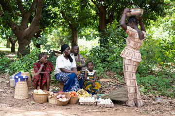 Typical African street market scene with black women and children trading home-grown vegetables and...