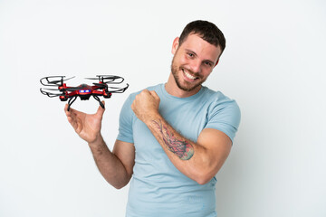 Young Brazilian man holding a drone isolated on white background celebrating a victory