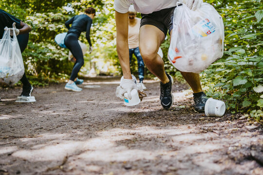Male and female environmentalists picking up plastics while plogging in park