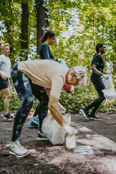 Female and male volunteers plogging while picking plastics in park