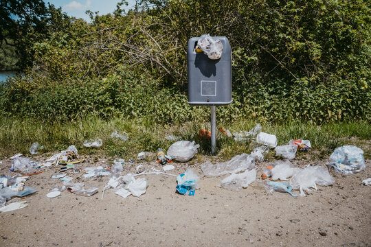 Garbage bin littered with plastic wastes around in park