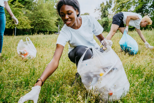 Female and male environmentalists picking up plastic waste at park