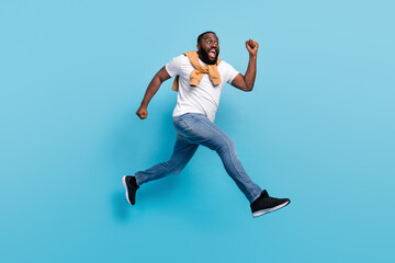 Fototapeta na wymiar Photo of shopaholic guy jump rush forward crazy mood wear t-shirt jumper front-tie isolated blue color background