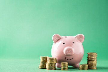 Pink piggy bank with coins on green background with copy space. Saving investment concept. High quality photo