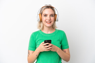 Young caucasian woman isolated on white background listening music with a mobile and looking front