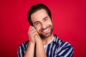 Photo of cheerful young man good mood hands touch cheek enjoy toothy smile isolated over red color background