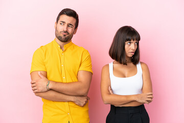 Young couple isolated on pink background with confuse face expression while bites lip