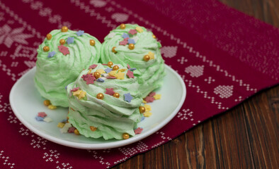 Green mojito flavored marshmallow (Zefir) garnished with multicolored sugar confectionery sprinkles. Festively decorated sweets to serve on the table for a holiday. New Year, Christmas, birthday.