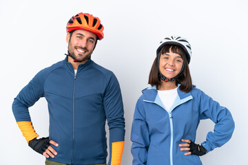 Young cyclist couple isolated on white background posing with arms at hip and smiling