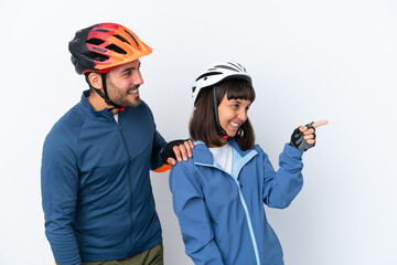 Young cyclist couple isolated on white background pointing to the side to present a product