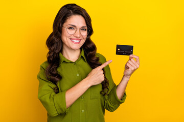 Fototapeta premium Photo of funny nice lady presenting debit card investment option wear glasses green shirt isolated yellow color background