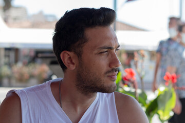 A portrait of handsome man in summer season. Close up photo. Man in a dazzle due to sunlights. 