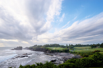 Beautiful balinese landscape. Ocean beach. Ancient hinduism temple Tanah lot on the rock against cloudy sky. Bali Island, Indonesia.