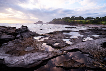 Obraz premium Beautiful balinese landscape. Ocean beach. Ancient hinduism temple Tanah lot on the rock against cloudy sky. Bali Island, Indonesia.
