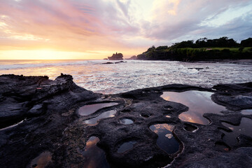 Beautiful balinese landscape. Ancient hinduism temple Tanah lot on the rock against sunset sky. Bali Island, Indonesia.