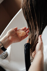 The hairdresser washes the hair of a fair-haired girl