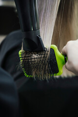 Close up of hairdressers hands drying long blonde hair with hairdryer and hair brush