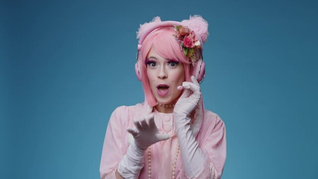 Glamorous funny fancy girl with pink hair and makeup plays like a call center operator comically talking to user or stranger and say hello. Glamour comic phone service support parody conecpt