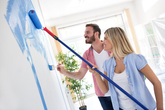 Young happy couple painting walls