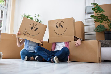Funny happy couple lying on floor wearing cardboard boxes