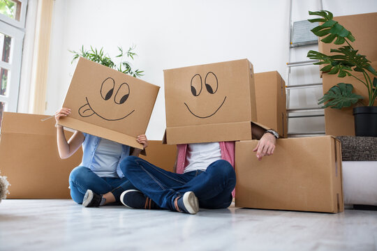 Funny happy couple lying on floor wearing cardboard boxes