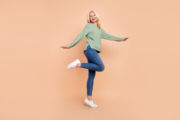 Fototapeta na wymiar Photo of cute charming retired woman wear green sweater dancing smiling isolated beige color background