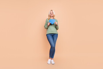 Fototapeta na wymiar Photo of adorable cute retired woman wear green sweater holding blue heart isolated beige color background