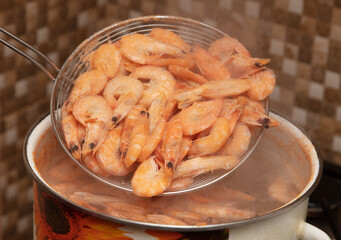 Red shrimps are boiled in a saucepan.