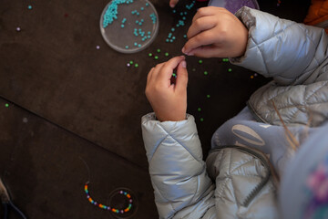 little children's hands weave a bead bracelet close-up shot