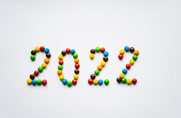 Year 2022 laid out from round multicolored candies on white background