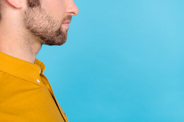 Obraz premium Cropped profile photo of chin young beard guy near empty space wear yellow shirt isolated on blue color background