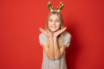 Happy child girl in santa hat isolated over red background.