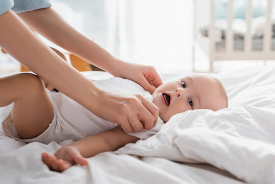 woman touching little son lying on bed with open mouth.