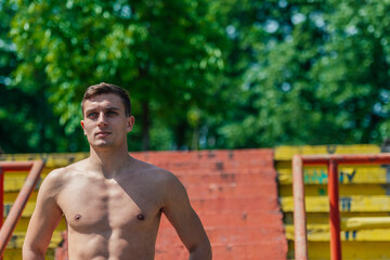 Obraz premium Portrait of a handsome young athlete without t-shirt standing on stairs