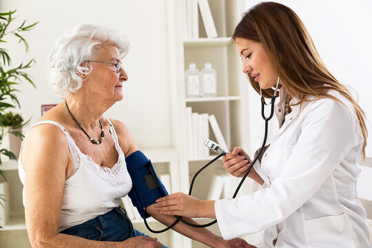 Female doctor checking blood pressure of senior woman
