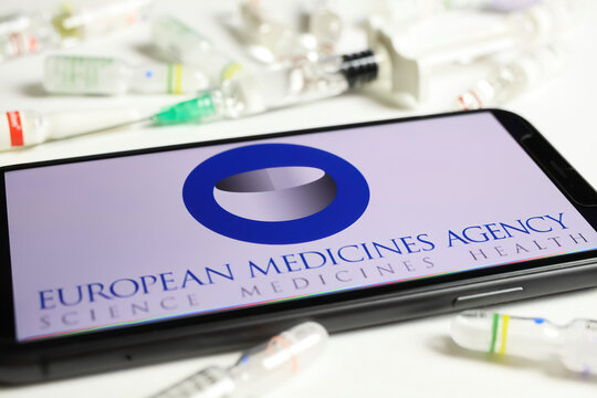 Viersen, Germany - December 1. 2021: Closeup of mobile phone screen with logo lettering of european medicine agency ema, serum vials and syringe background