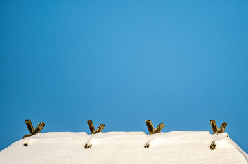 the roof ridge covered with snow with wooden decorative details against a blue sky background
