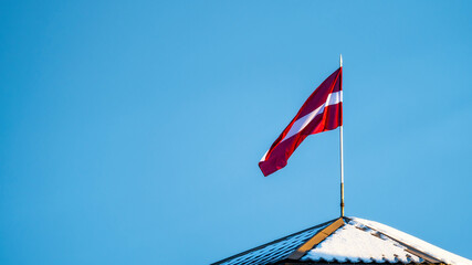 Latvian Flag on the flagpole fluttering in the wind against blue clear sky, copy space
