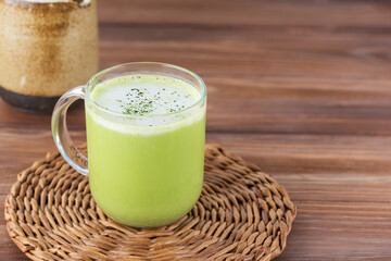 Matcha latte with coconut milk in a cup on a wooden table.