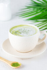 Matcha latte with coconut milk in a mug on a light background.